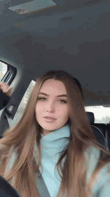 a woman with long hair is sitting in the back seat of a car looking at the camera .