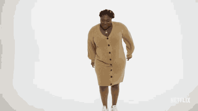 a woman in a sweater dress is dancing in front of a white background with netflix written on it