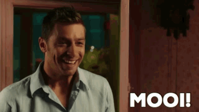 a man in a blue shirt is smiling in front of a sign that says mooi !