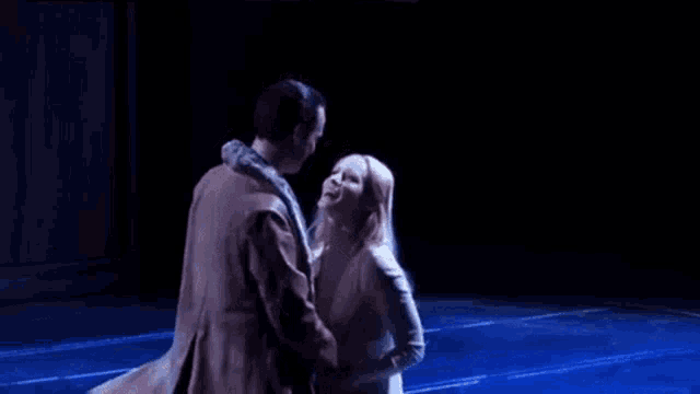 a man and woman are kissing on a stage in the dark .