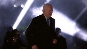 a man in a suit and tie is dancing in front of a crowd of people