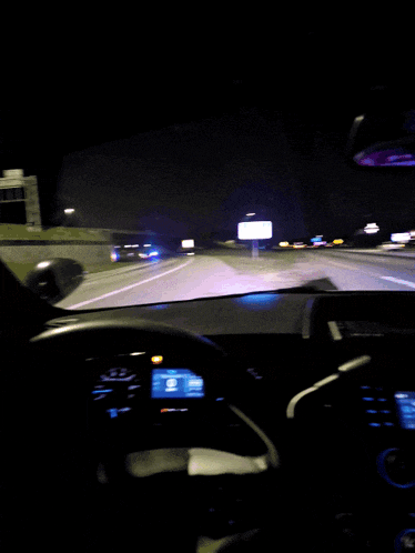 a car is driving down a highway at night and the dashboard is lit up