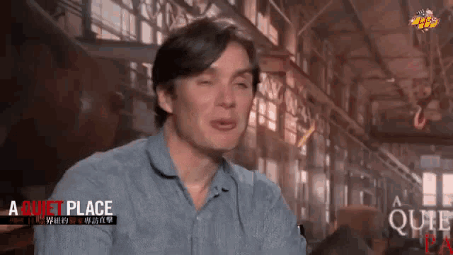 a man in a blue shirt is making a funny face in front of a sign that says quiet place