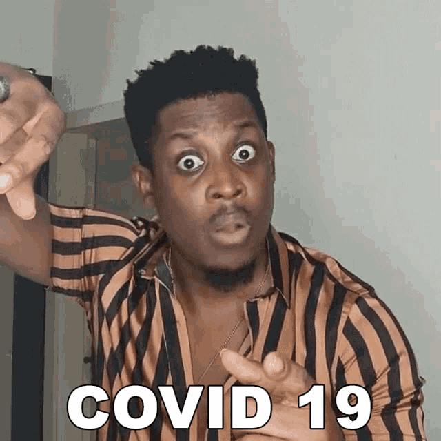 a man wearing a striped shirt is pointing at the camera and says covid 19