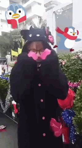 a woman wearing a cat hat and gloves is standing in front of a christmas decoration