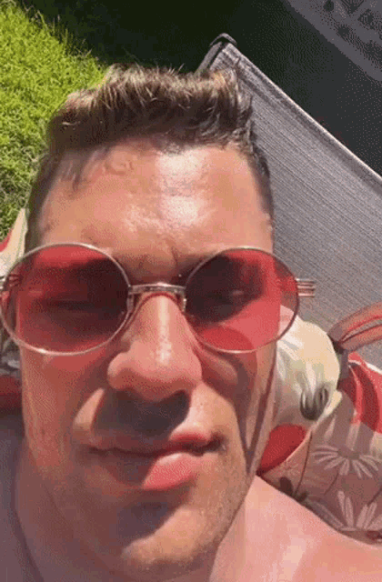 a man wearing red sunglasses is laying on a lawn chair