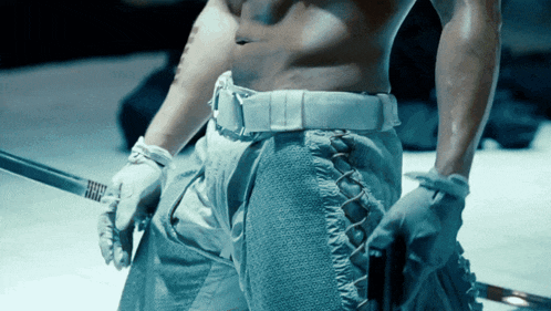 a shirtless man is holding a sword in his hands