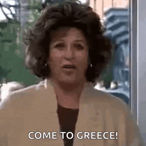 a woman is standing in front of a window and says come to greece .