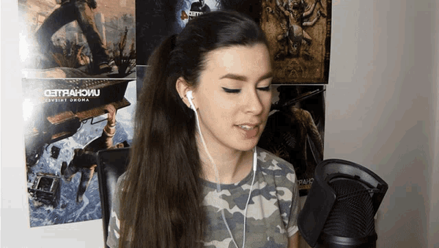 a woman wearing ear buds stands in front of a wall with posters on it including one for metro 2033
