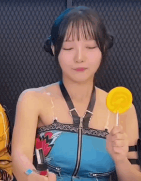 a girl is holding a yellow lollipop in her hand .