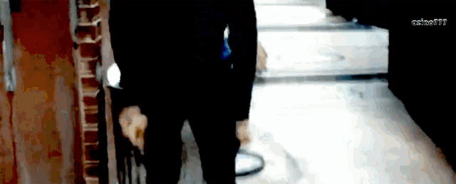 a blurry picture of a man walking down a hallway with a brick wall in the background