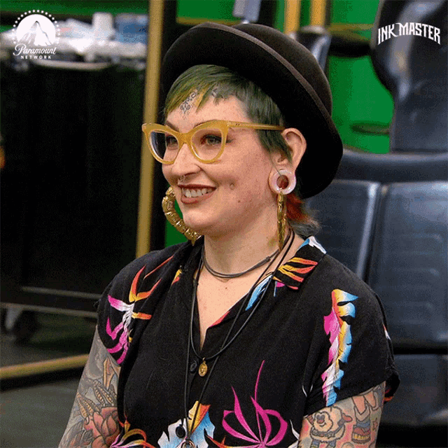 a woman wearing a hat and glasses is smiling in front of a paramount network logo