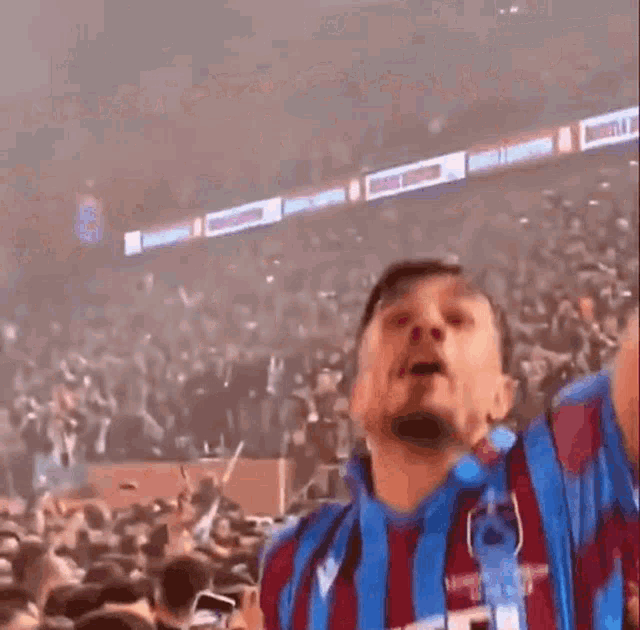 a soccer player wearing a vestel jersey is standing in front of a crowd .