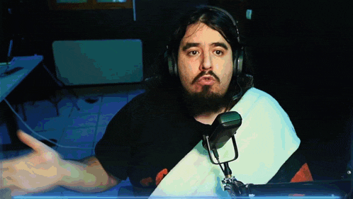 a man with a beard wearing headphones and a microphone giving a thumbs up