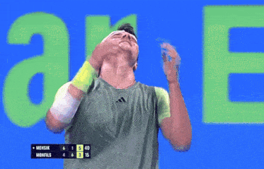 a man covering his face with his hands in front of a green a