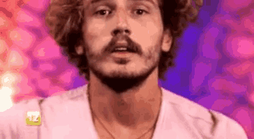 a man with curly hair and a beard is wearing a white shirt and necklace .