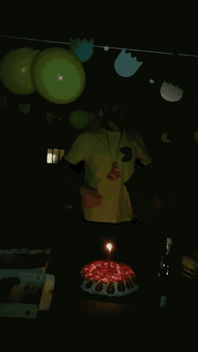 a man in a yellow shirt is standing in front of a cake
