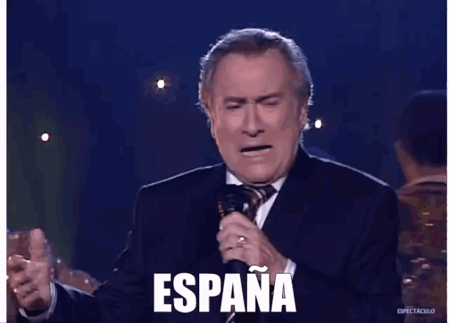 a man in a suit singing into a microphone with the word espana on the bottom