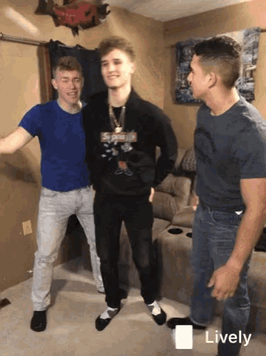 a man wearing a supreme sweatshirt stands with two other men in a living room