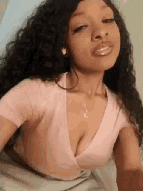 a woman with curly hair is wearing a pink crop top with a plunging neckline