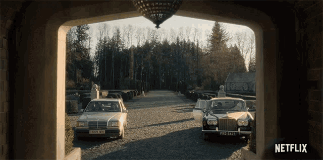 a mercedes and a rolls royce are parked in the driveway of a house
