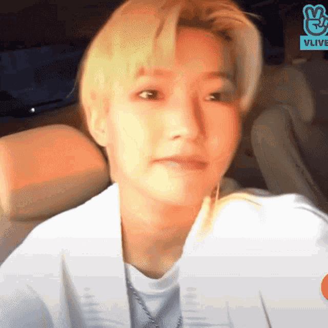 a young man with blonde hair is sitting in a car and making a face .
