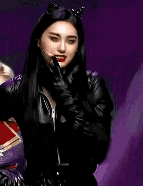 a woman in a catwoman costume is holding a microphone and wearing gloves .