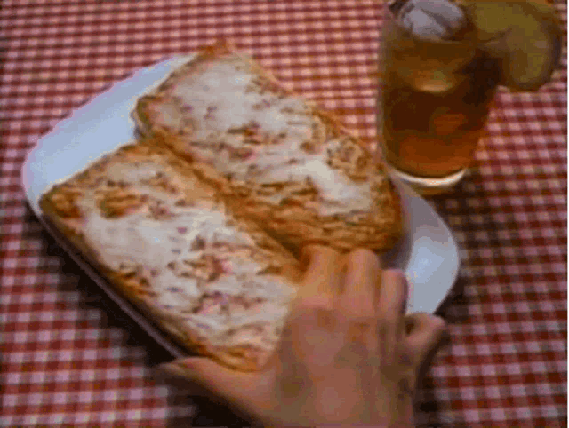 a person reaches for a piece of pizza on a paper plate