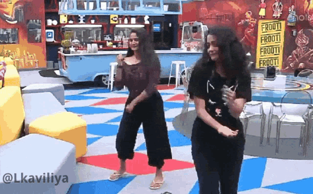two women are dancing in front of a food truck that says frooti on it