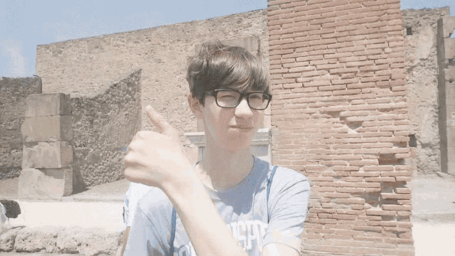 a boy wearing glasses and a shirt that says ' london ' on it gives a thumbs up