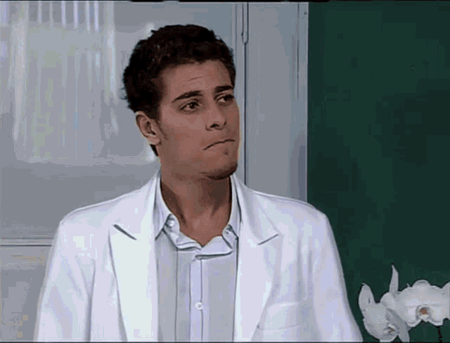 a man in a white lab coat making a face