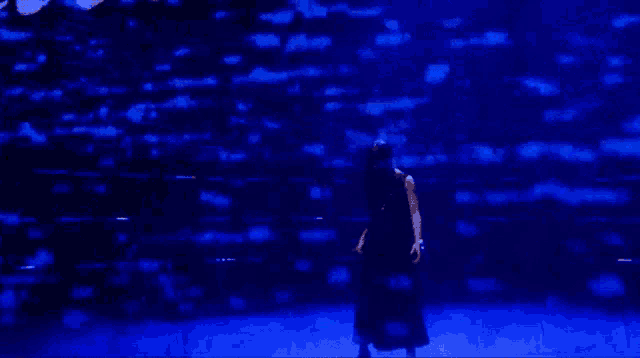 a person is standing in a dark room with blue lights behind them .