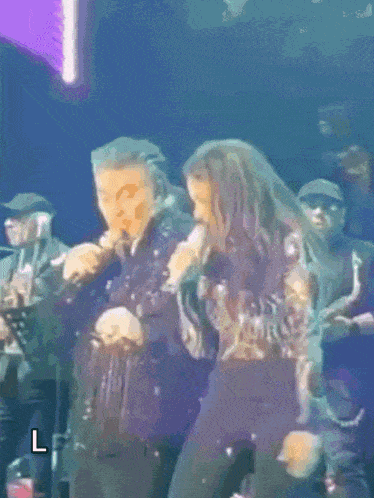 a man and a woman singing on a stage with the letter l in the corner