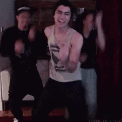 a man in a tank top is dancing with two other men .