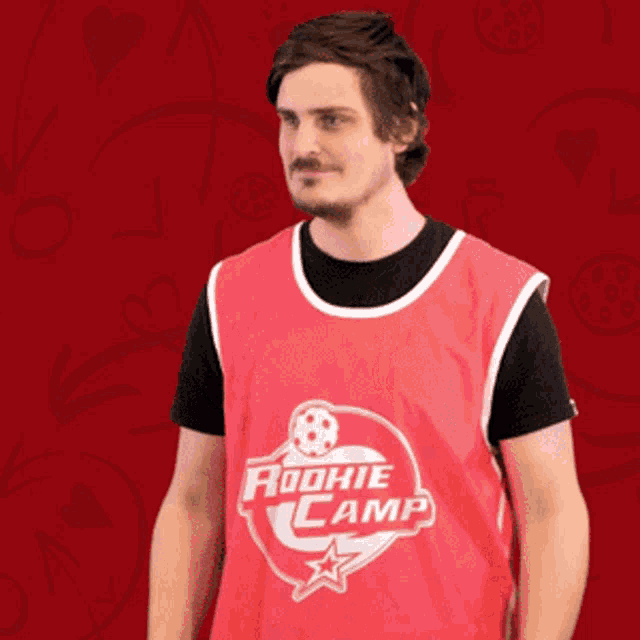 a man is wearing a red rookie camp jersey