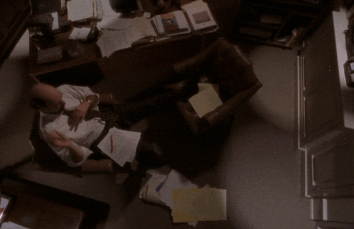 a man sits at a desk with papers on the floor