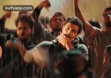 a group of men are dancing in the rain with their arms in the air .