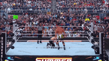 two wrestlers in a ring with a sign that says summerslam on it