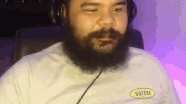 a man with a beard is wearing headphones and a shirt that says dotere .