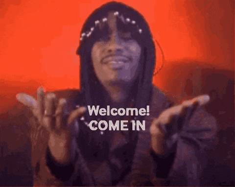 a man with long hair and a hat says welcome come in