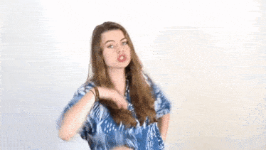 the woman is wearing a blue shirt and earrings and is holding her hair .