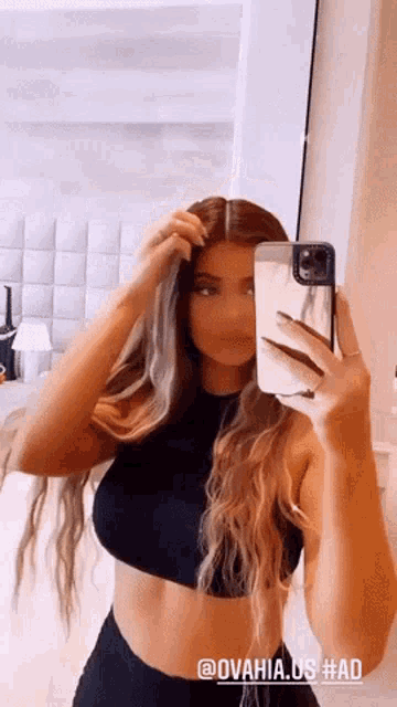 a woman is taking a selfie in a mirror with her phone .