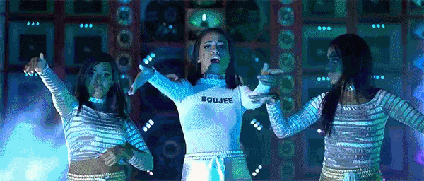 a woman in a white shirt that says boujee is dancing with two other women