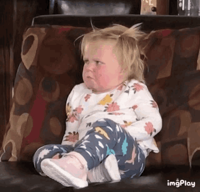 a little girl is sitting on a couch with her legs crossed .