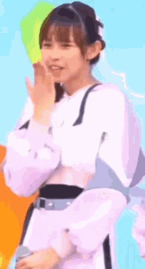 a girl in a white shirt is waving her hand and smiling