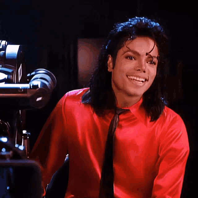 a man in a red shirt and tie is smiling