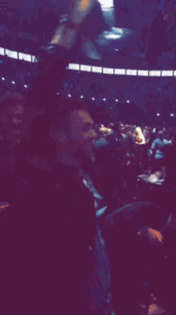 a man in a suit holds his arm up in the air in a dark room
