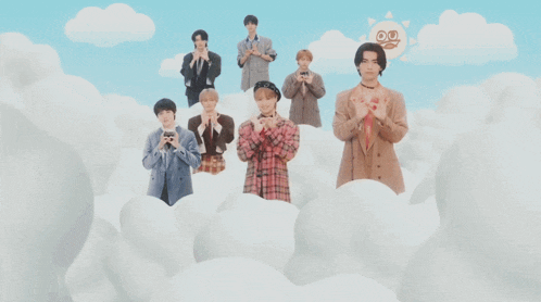 a group of young men are standing in the clouds with their hands in the shape of a heart