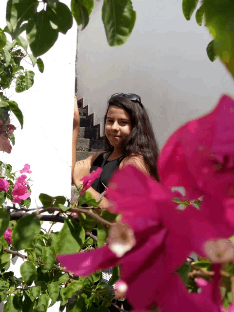a girl is standing in front of a white wall with pink flowers