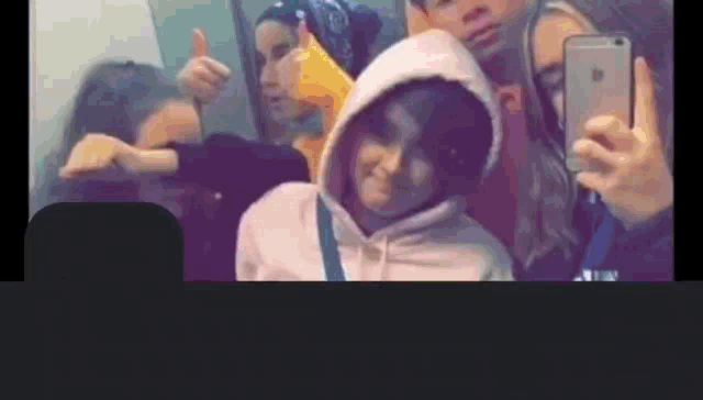 a group of people are taking a selfie with a phone .